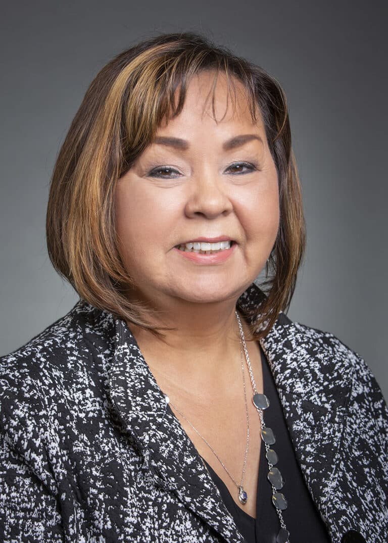 Woman wearing a gray and black speckled shirt smiling