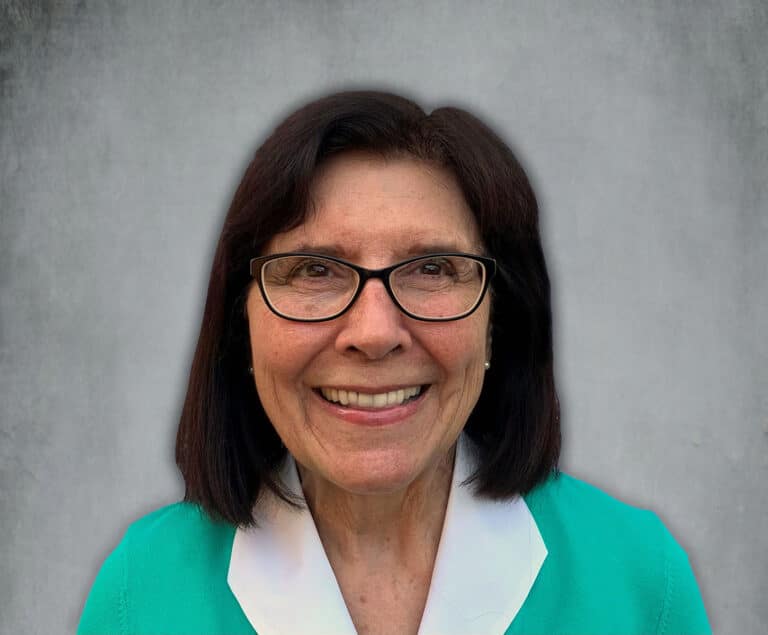 Woman wearing a green and white shirt with glasses smiling